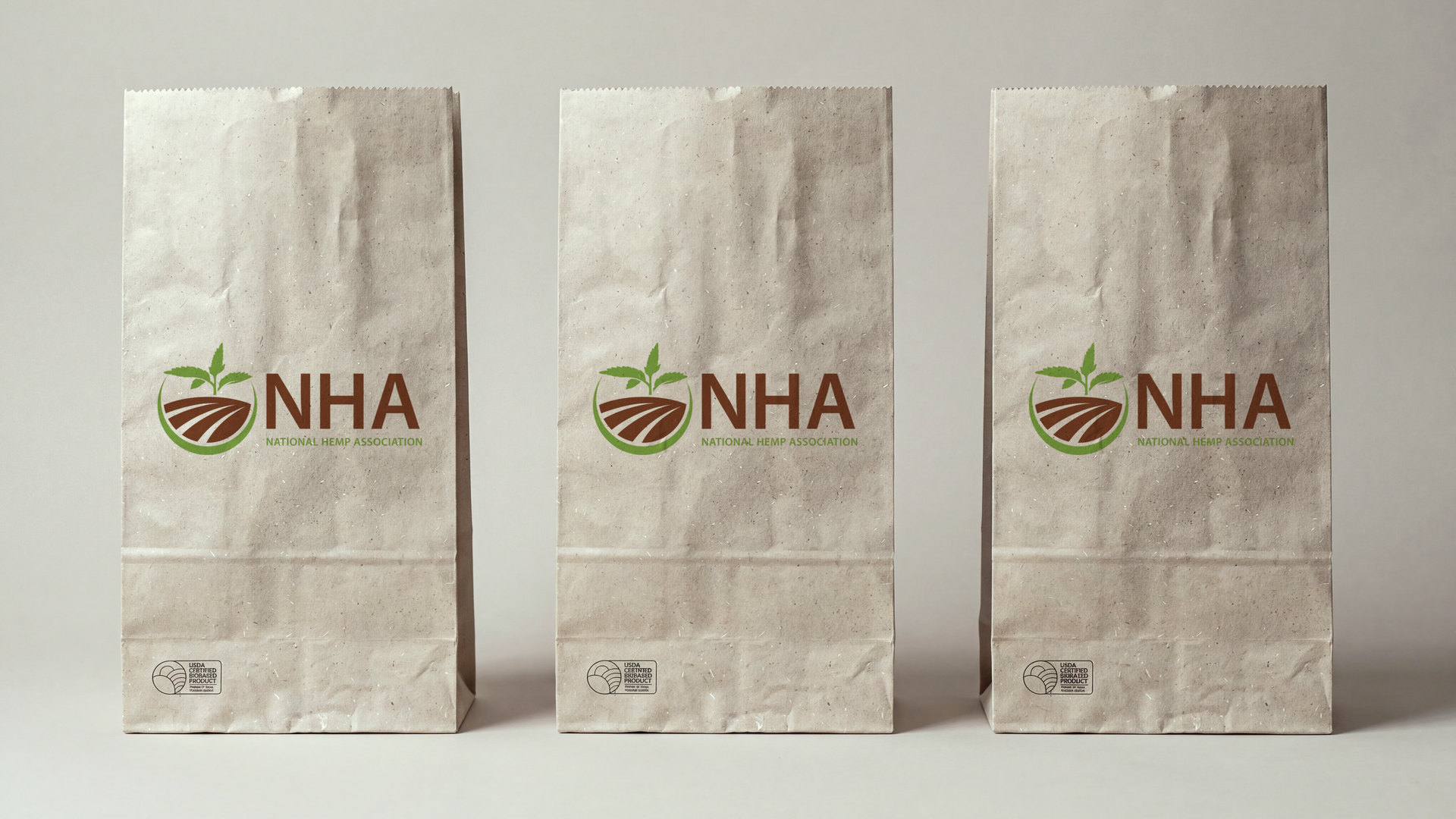 Three kraft hemp paper bags printed with the National Hemp Association logo. Product visualization, AI-assisted.